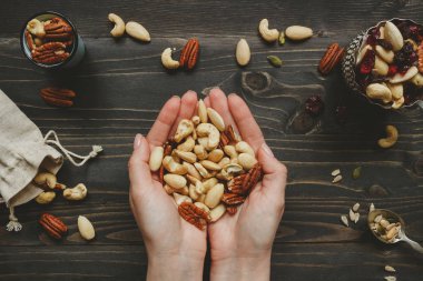 Fındık, tohumlar ve kurutulmuş meyveler ile karıştırın. Ahşap masa üzerinde fındık holding eller