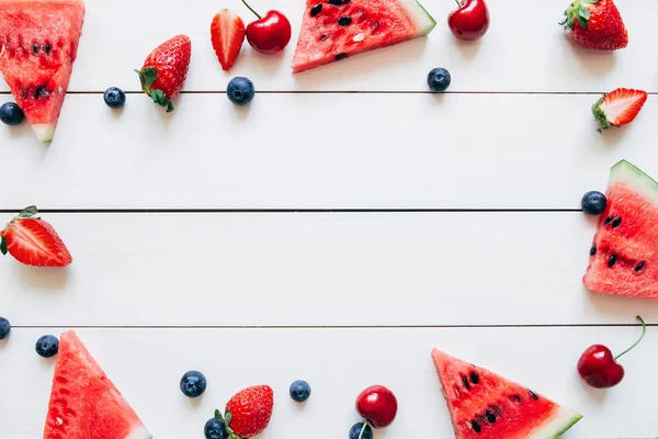 Frutas de verano. Frescas bayas jugosas y sandía en la mesa de madera blanca, vista superior — Foto de Stock