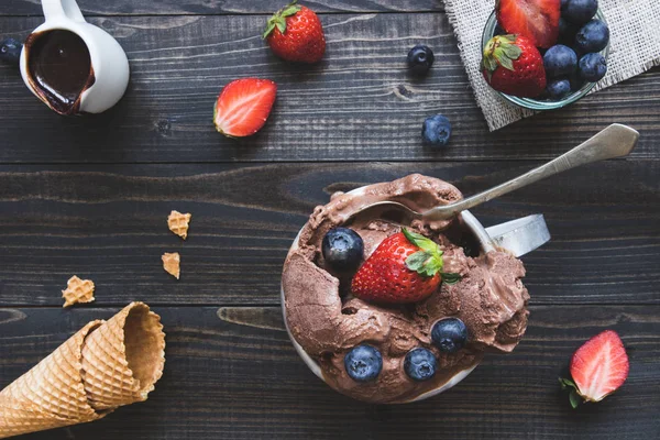 Delicious ice-cream with fresh berries and chocolate sauce on the wooden background, top view — Stock Photo, Image