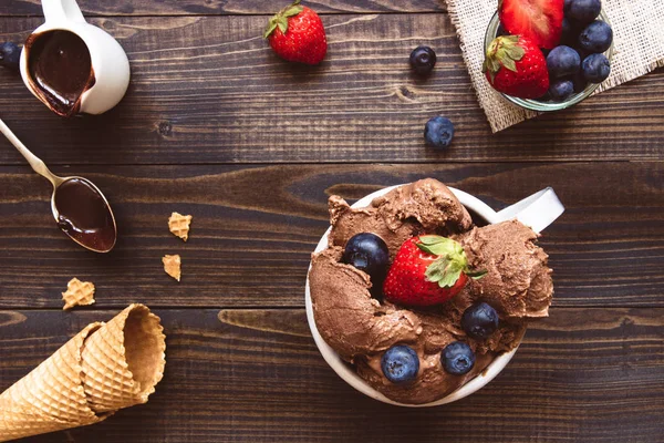 Delicious ice-cream with fresh berries and chocolate sauce on the wooden background, top view — Stock Photo, Image