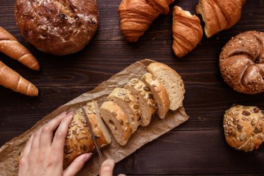 Koyu ahşap arka plan üstünde taze ekmek dilimleme eller göster