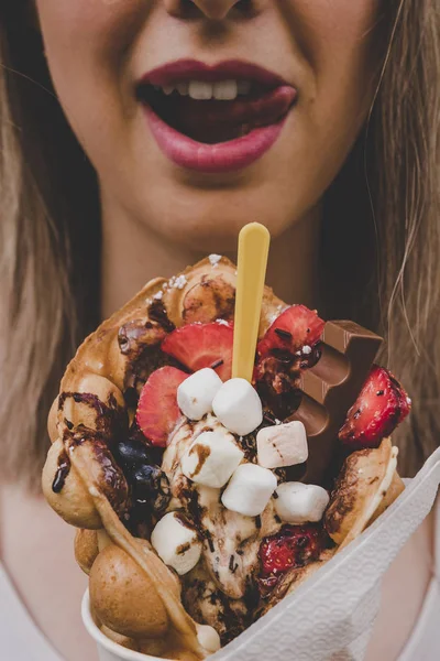 Meyve, çikolata ve şekerleme, seçici odak ile kabarcık gözleme tutan genç kadın