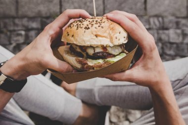 Adam taze lezzetli ızgara hamburger yeme. Üstten Görünüm