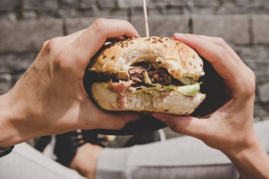 Adam taze lezzetli ızgara hamburger yeme. Üstten Görünüm
