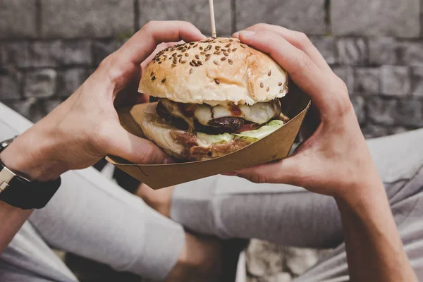 Mężczyzna jedzenie świeże, smaczne burger z grilla. Widok z góry — Zdjęcie stockowe