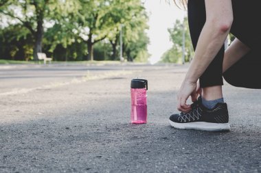 Çalıştırmak için hazırlanıyor. Genç kadın parkta onu koşu ayakkabıları bağlama