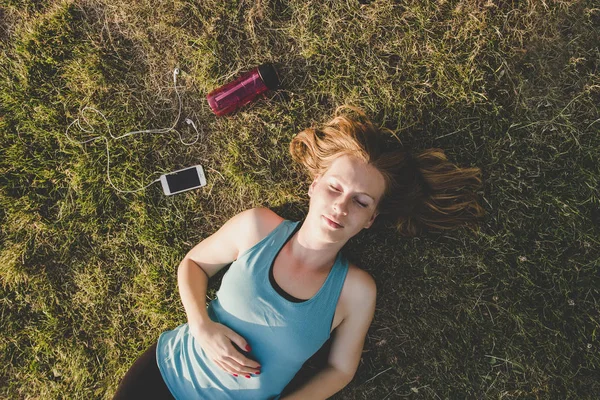 Relaxante ao ar livre. Jovem mulher relaxando no parque depois de correr — Fotografia de Stock