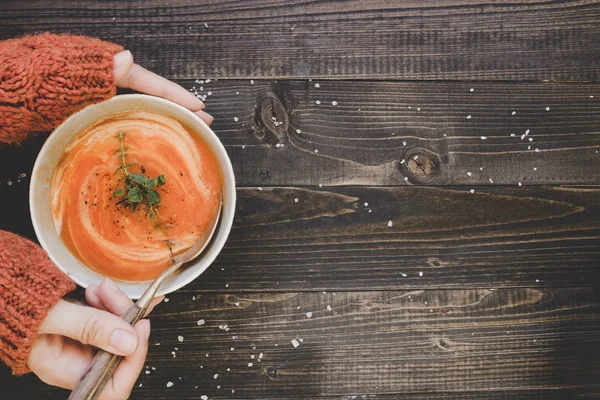 Eller ahşap masada sıcak krema çorbası tutarak, üst görünümü. Kopyalama alanı ile