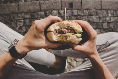 Adam taze lezzetli ızgara hamburger yeme. Üstten Görünüm