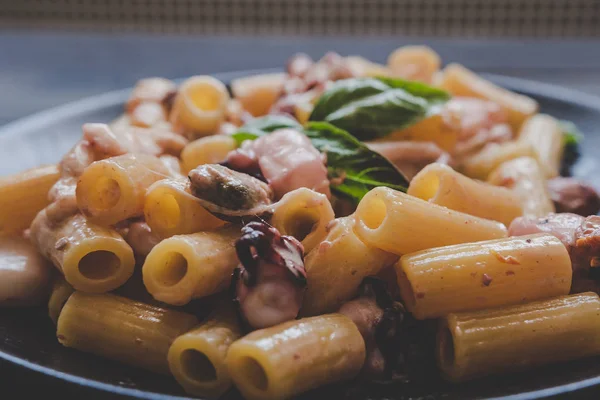 Deniz ürünleri ve fesleğen siyah plaka, seçici odak ile rigatoni makarna