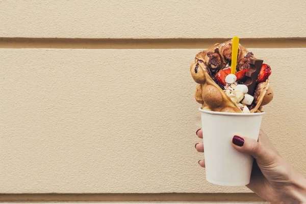 Hand holding bubble waffle with fruits, chocolate and marshmallow, with copy space — Stock Photo, Image