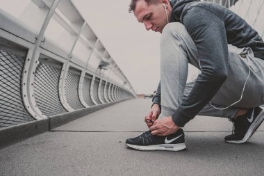 Genç adam şehirde çalıştırmaya hazırlanma Koşu Ayakkabı bağlama