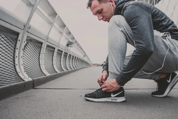 Genç adam şehirde çalıştırmaya hazırlanma Koşu Ayakkabı bağlama