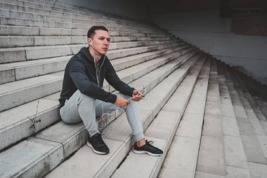 Onun smartphone kullanarak şehrin modern köprüde oturan genç adam