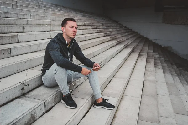 Onun smartphone kullanarak şehrin modern köprüde oturan genç adam