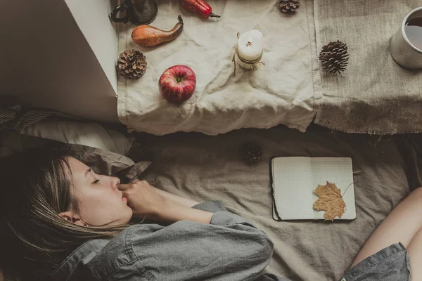 Uma casa acolhedora. Humor de outono. Mulher dormindo na cama pela janela — Fotografia de Stock