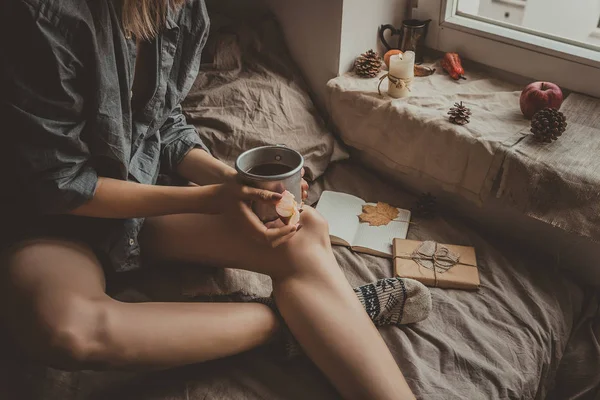 Rahat ev. Sıcak içecek cam kenarında oturan bir kadınla. Seçici odak