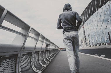 Şehrin modern köprüde koşan genç adam