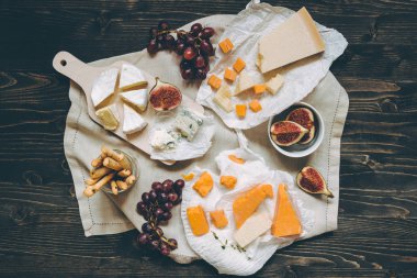 Meyve ve koyu ahşap masa snacks ile peynir seçimi. Üstten Görünüm