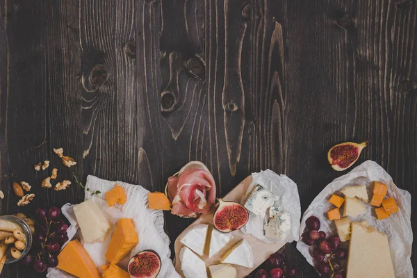 コピー スペースを持つ木製の暗いテーブルで軽食や果物とチーズの様々 な種類 — ストック写真