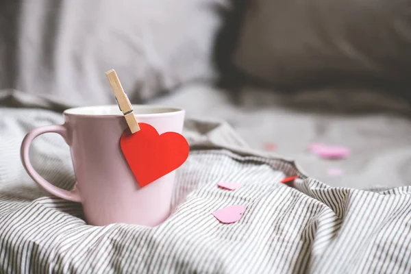 Fond Saint-Valentin avec espace de copie. Tasse rose avec coeur sur le lit. Concentration sélective — Photo