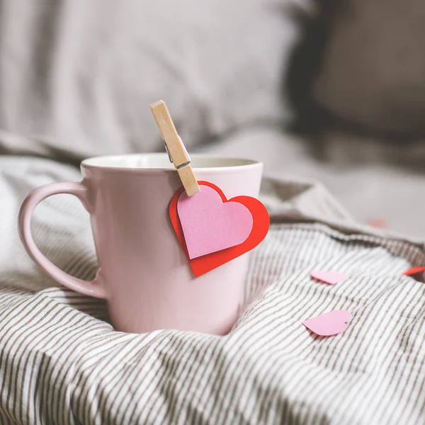 Fond Saint-Valentin. Tasse rose avec des coeurs sur le lit. Concentration sélective — Photo