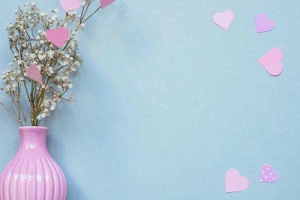 Flores en jarrón con corazones de papel rosa sobre el fondo azul. Copiar espacio — Foto de Stock