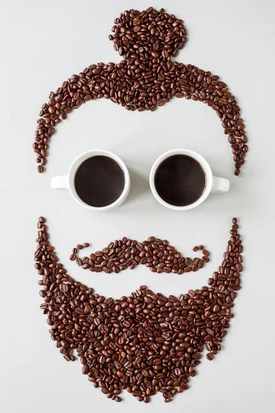 Homem hipster barbudo feito de grãos de café com copos feitos de xícaras de café — Fotografia de Stock