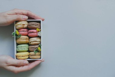 Hediye kutusu ile hafif blu üzerinde lezzetli macaroons holding eller