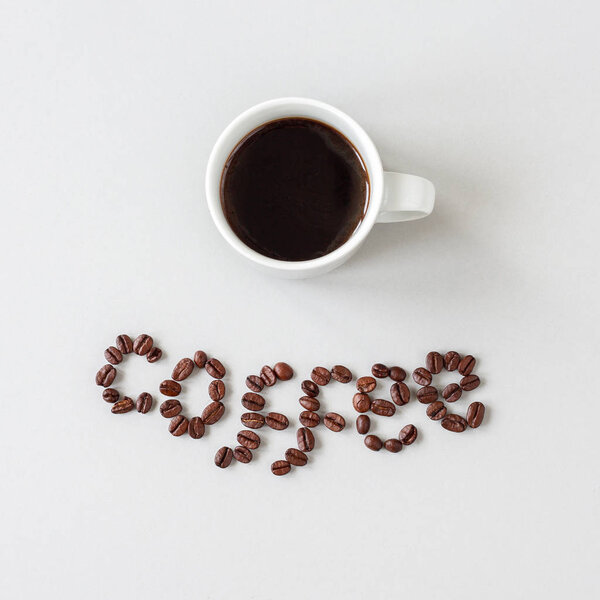 Coffee word made of coffee beans and cup of coffee, top view