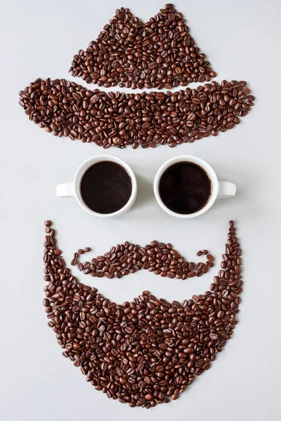 Homem hipster barbudo em chapéu feito de grãos de café com copos feitos de xícaras de café — Fotografia de Stock