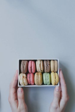 Hediye kutusu ile hafif blu üzerinde lezzetli macaroons holding eller