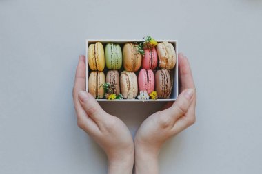 Hediye kutusu ile hafif blu üzerinde lezzetli macaroons holding eller