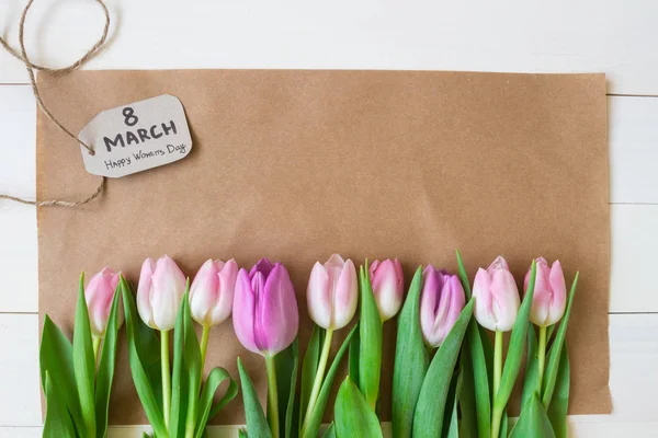 Жіночий день. красиві свіжі тюльпани з папером на дерев'яному фоні — стокове фото