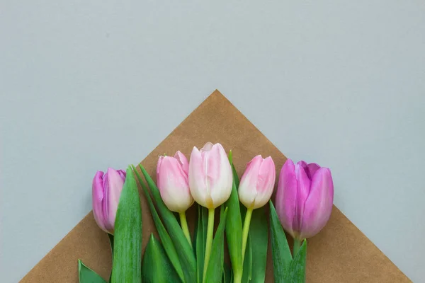 Bouquet of beautiful fresh tulips with craft paper on the wooden background. Copy space — Stock Photo, Image