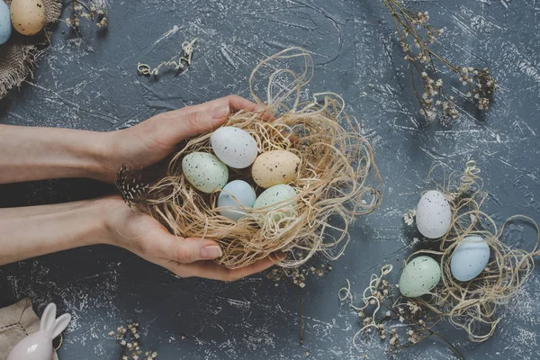 Vrolijk Pasen. Handen met Pasen eieren in nest met Pasen decoratie, bovenaanzicht — Stockfoto