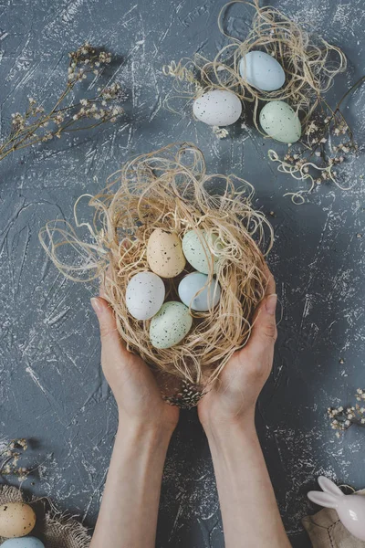 Vrolijk Pasen. Handen met Pasen eieren in nest met Pasen decoratie, bovenaanzicht — Stockfoto