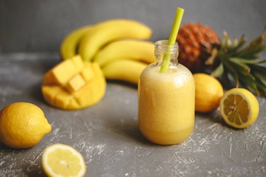 Limon, muz ve gri arka plan üzerinde ananas ile taze sarı güler yüzlü