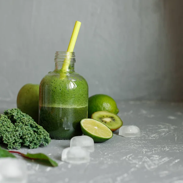 Smoothie verde saludable con ingredientes y cubitos de hielo sobre fondo gris —  Fotos de Stock