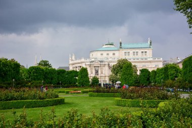 Avusturya, Viyana 'daki Volksgarten manzarası, yağmurdan önce mavi dramatik gökyüzü. Arka planda ise Avusturya Ulusal Tiyatrosu ve dünyanın en büyük tiyatrolarından biri yer almaktadır.