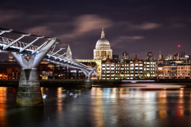 Londra, Londra 'daki St. Paul Katedrali' nin aydınlatılmış kubbesinin Thames Nehri ve modern Milenyum Köprüsü 'nün olduğu güzel gece manzarası.