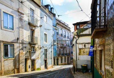 Lizbon / Portekiz - 1 Aralık 2019: Lizbon 'daki Alfama Mahallesi' nin güneşli sokakları, eski evleri ve azulejo fayanslarıyla. Alfama Lizbon 'un en eski bölgesidir ve sarı tramvaylar ile hizmet vermektedir.