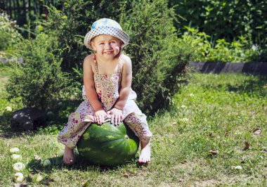 Küçük kız büyük bir karpuz üzerinde oturuyor