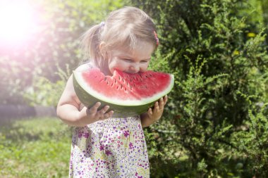Yaz, küçük kız büyük dilim karpuz yiyor.