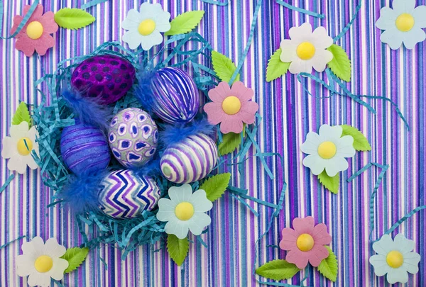 Easter background, spring flowers with easter eggs, Easter eggs decorated with a felt-tip pen, an ultra-violet striped background