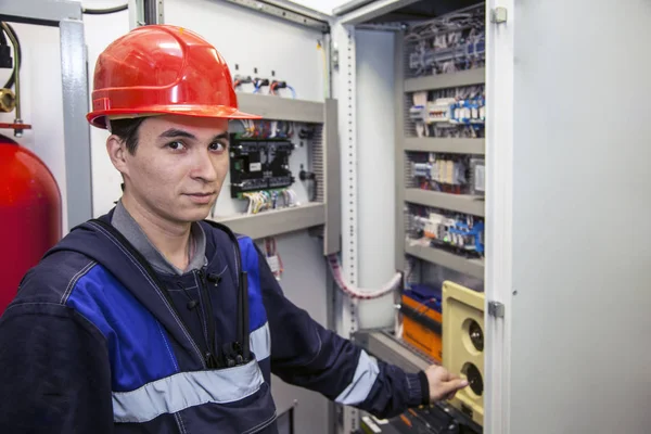 electromechanic in electrical safety gloves holds power cable, cabling connection of high voltage power electric line in industrial distribution fuseboard