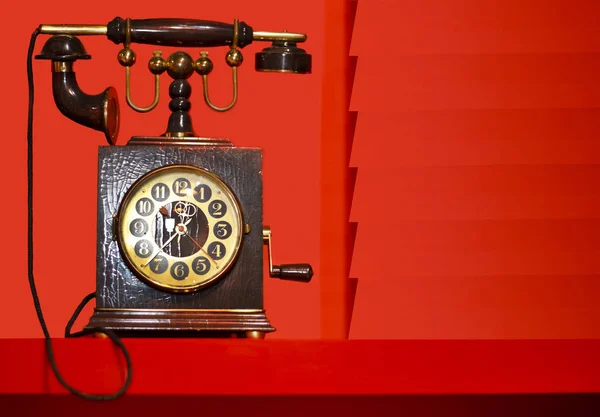 old (retro) phone with built-in clock on a red background