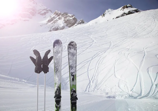 Skiing and ski poles stand vertically in the snow against the background of the ski descent