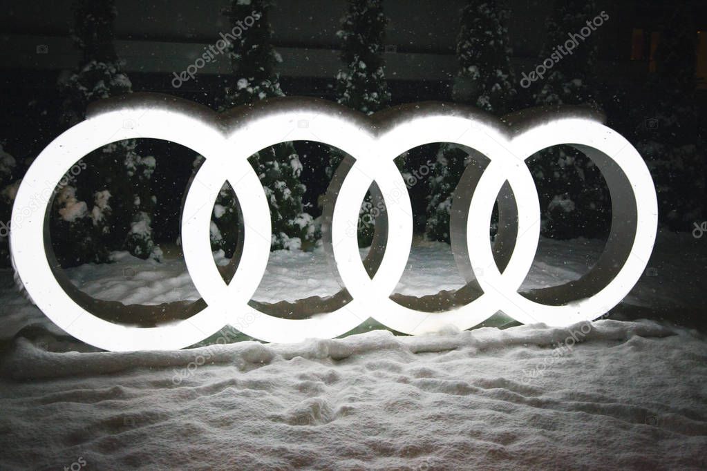 KRASNAYA POLYANA, SOCHI,  RUSSIA- 07  december 2017: company logo of Audi with illumination, against the backdrop of a New Year tree, evening, it's snowing, photo with noise.