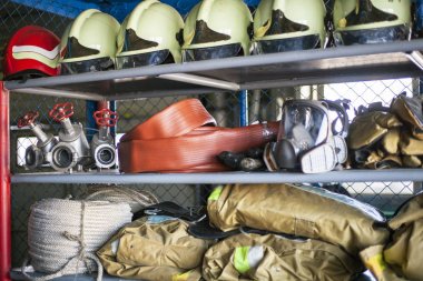 Emanet ateş. Bir yangın söndürme için acil hisse senedi ile bir raf. Kask, eldiven, gözlük, kulaklık, itfaiyeci kıyafeti, ip.